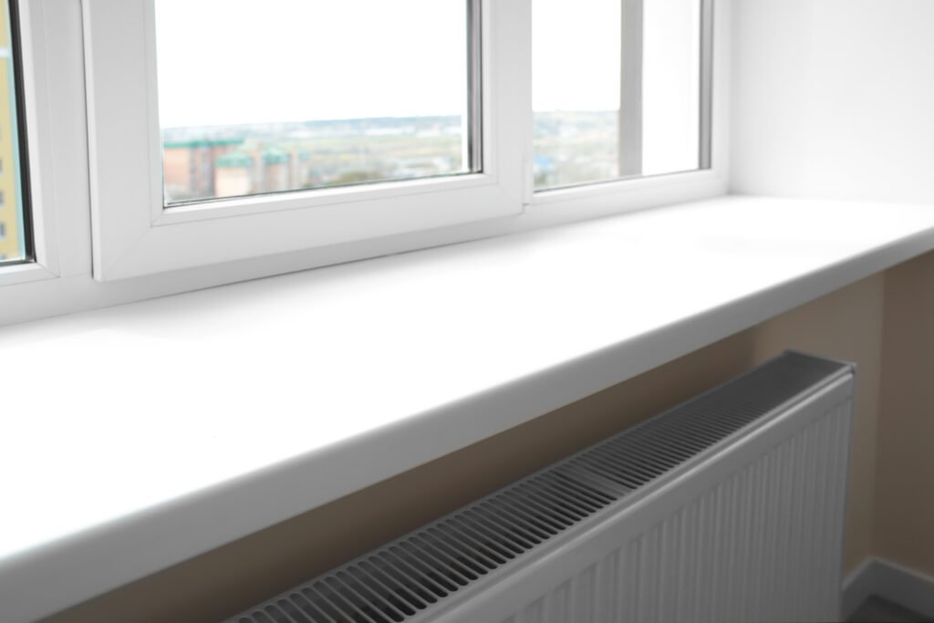 Detail van een moderne witte binnenvensterbank strak gemonteerd onder een PVC kozijn, perfecte afwerking voor woningbouwprojecten.